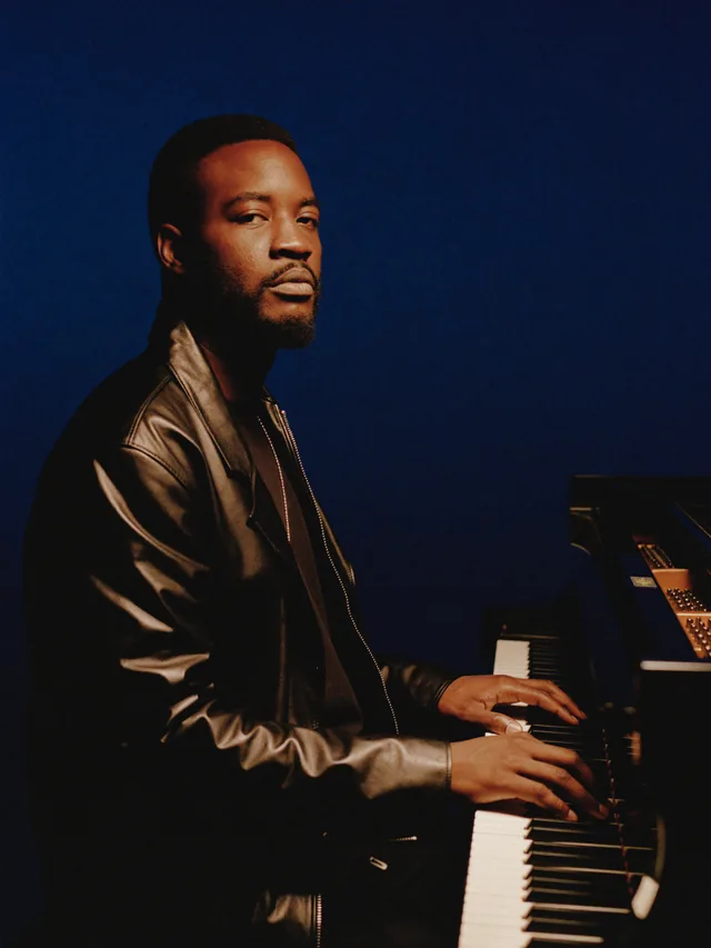The KompaMi pianist, in profile, hands on a keyboard, dark leather jacket.